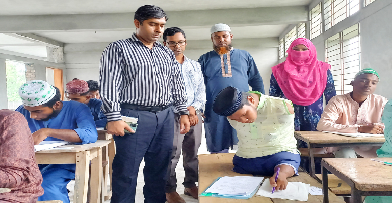 দুই হাত-এক পা নেই, অন্য পা দিয়ে লিখে দাখিল পরীক্ষা দিচ্ছে সিংড়ার অদম্য রাসেল